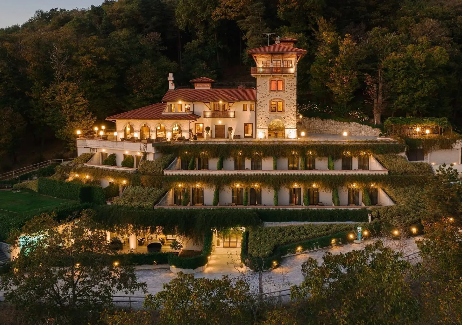 Tenuta de l’Annunziata at dusk: the stone tower, the house and its lit terraces