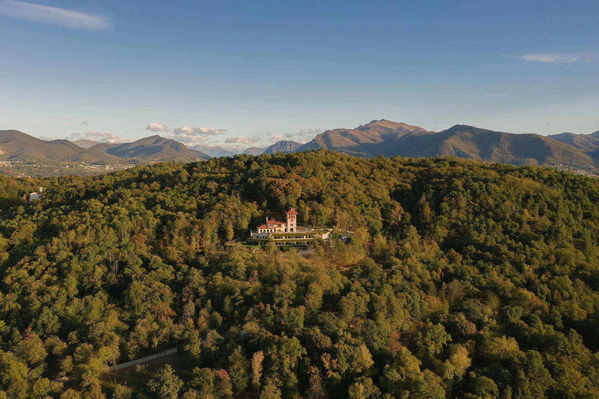 The Tenuta on its wooded hill, with the mountains around Lugano behind